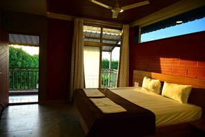 Un dormitorio con una cama grande, un ventilador de techo y un balcón con vistas al verdor.