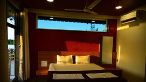 Una habitación de hotel con cama, ventilador de techo, ventana y aire acondicionado.