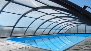 A transparent greenhouse structure with a blue pool inside. - Ferienhof Löw (Salzweg)