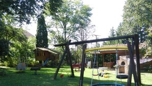A playground with swings, a slide, and a swing set. - Ferienhof Löw (Salzweg)