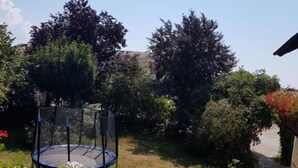 A trampoline in a garden with various plants and a clear sky. - Ferienhof Löw (Salzweg)