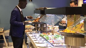 Un bufé con diferentes alimentos y una persona atendiendo.