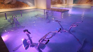 Una piscina interior con equipo de ejercicios y murales en las paredes.