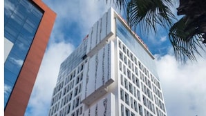 Un edificio de hotel alto con una fachada moderna, varias banderas y el nombre "NEW HOTEL" bien visible.