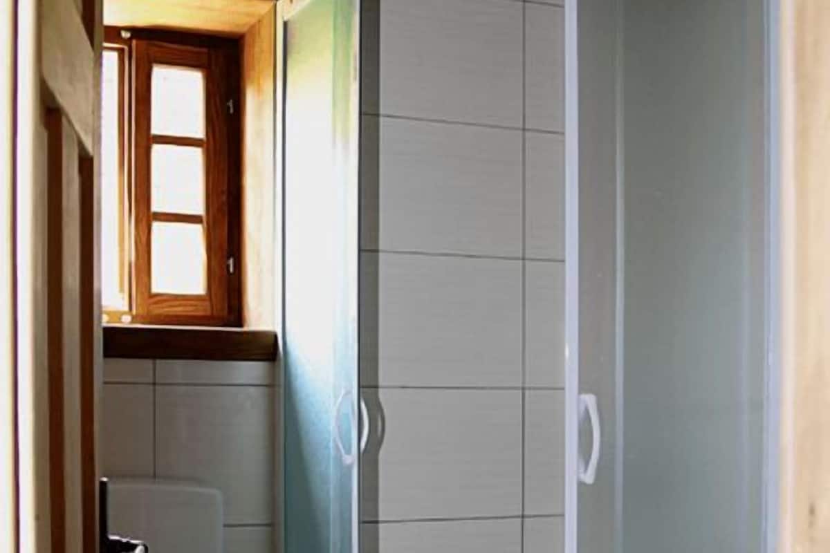 Ein Badezimmer mit Toilette, Duschkabine und Fenster.