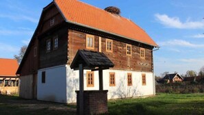 A two-story wooden house with a red-tiled roof and white lower walls. - Pension Tišina (Sisak)