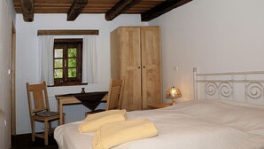 A bedroom with a bed, wooden wardrobe, desk, chair, and a window with curtains. - Pension Tišina (Sisak)