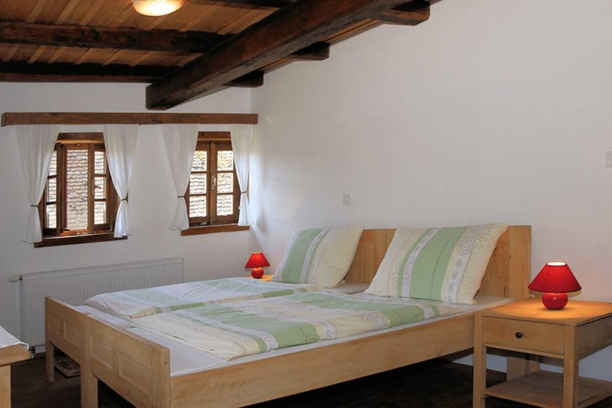 Ein Schlafzimmer mit einem hölzernen Bett, zwei Nachttischlampen und einem Fenster mit Vorhängen.