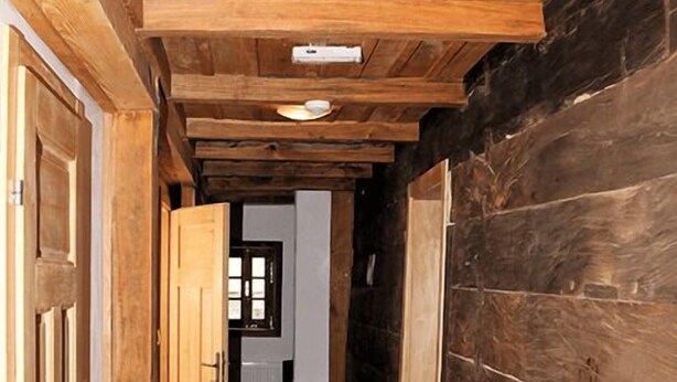 A narrow wooden hallway with a wooden door on the left and a window at the end. - Pension Tišina (Sisak)