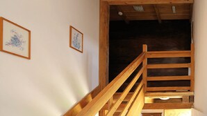 A wooden staircase leading to a dark room with two framed artworks on the walls. - Pension Tišina (Sisak)
