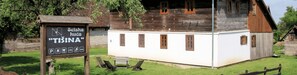 A wooden sign with "Selska kuća 'TISINA' parking symbols and a white building with wooden shutters. - Pension Tišina (Sisak)
