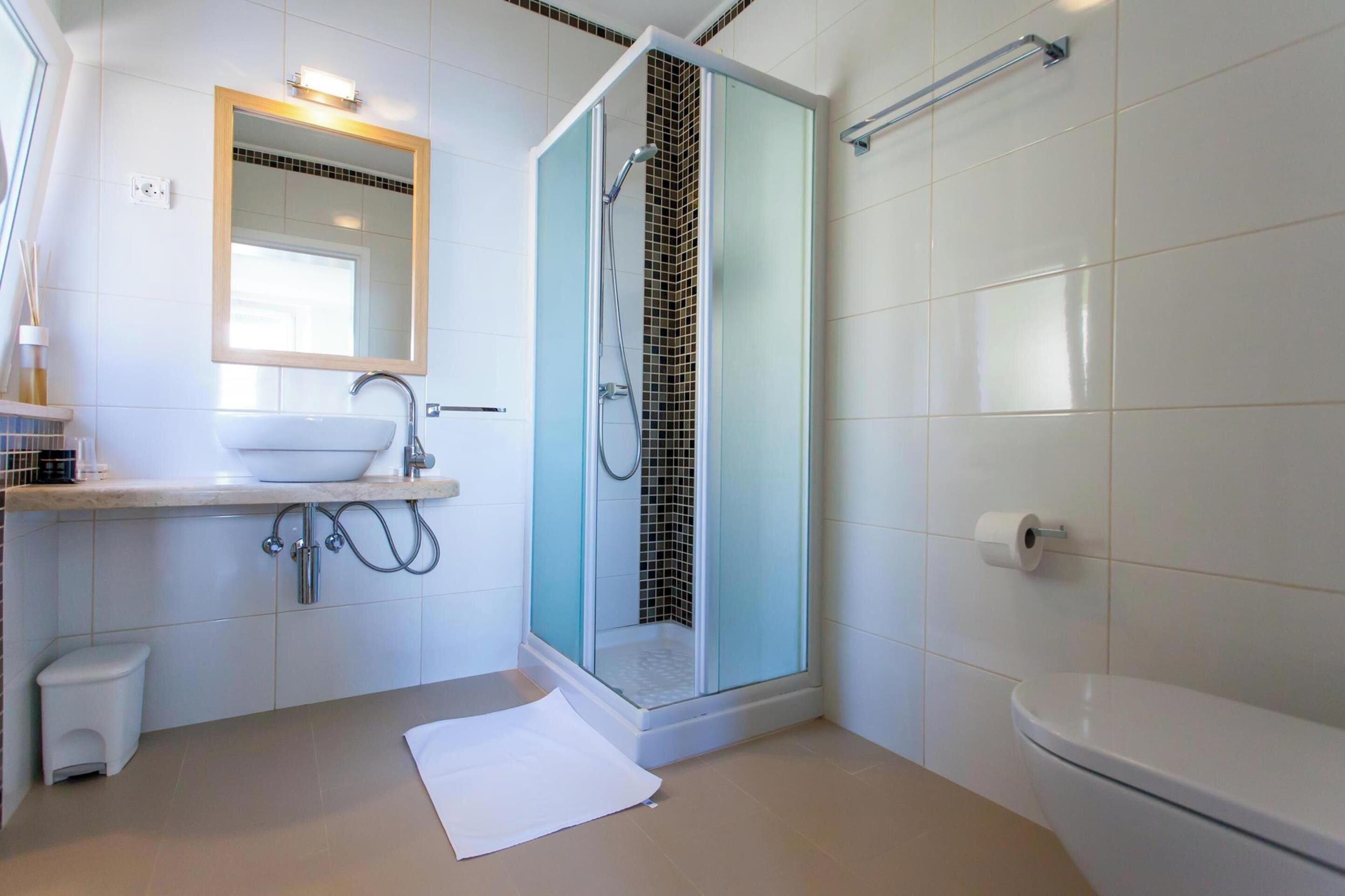 A modern bathroom with a glass-enclosed shower, a sink with a mirror above it, and a toilet.