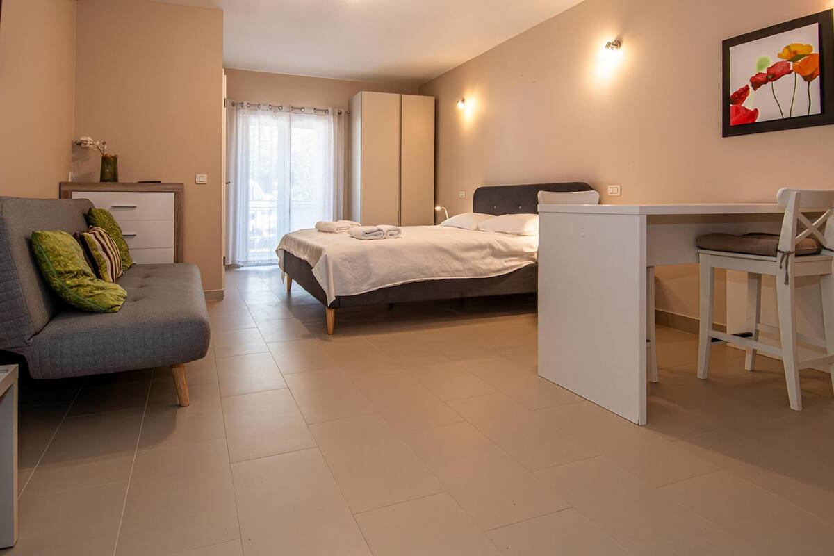 Un dormitorio moderno con cama, escritorio y sofá gris.