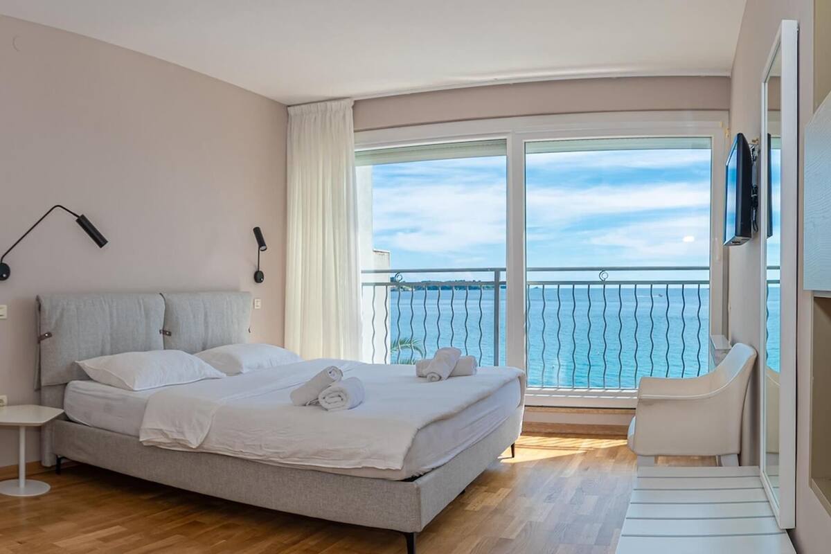 Un dormitorio moderno con cama, mesita de noche y vista al mar.