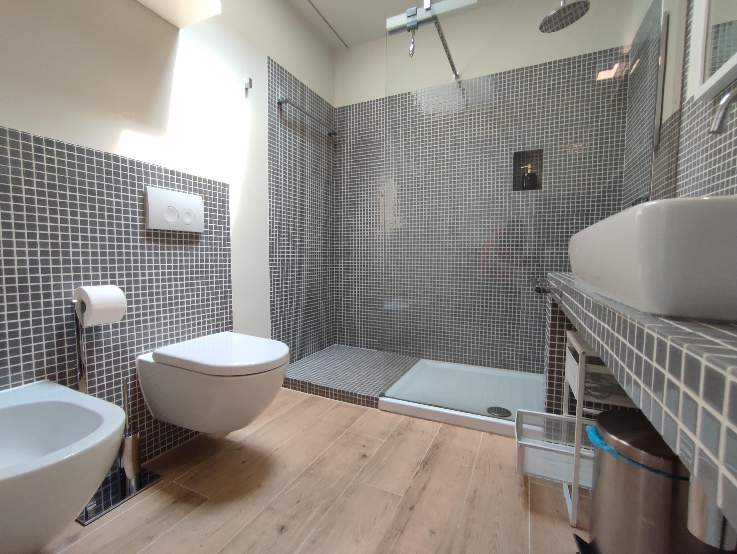 A modern bathroom with a toilet, bidet, and shower area.