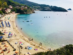 Una playa con aguas cristalinas, sombrillas y barcos.