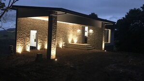 Una casa moderna con fachada de piedra, un porche cubierto y una escalera que conduce a la entrada.