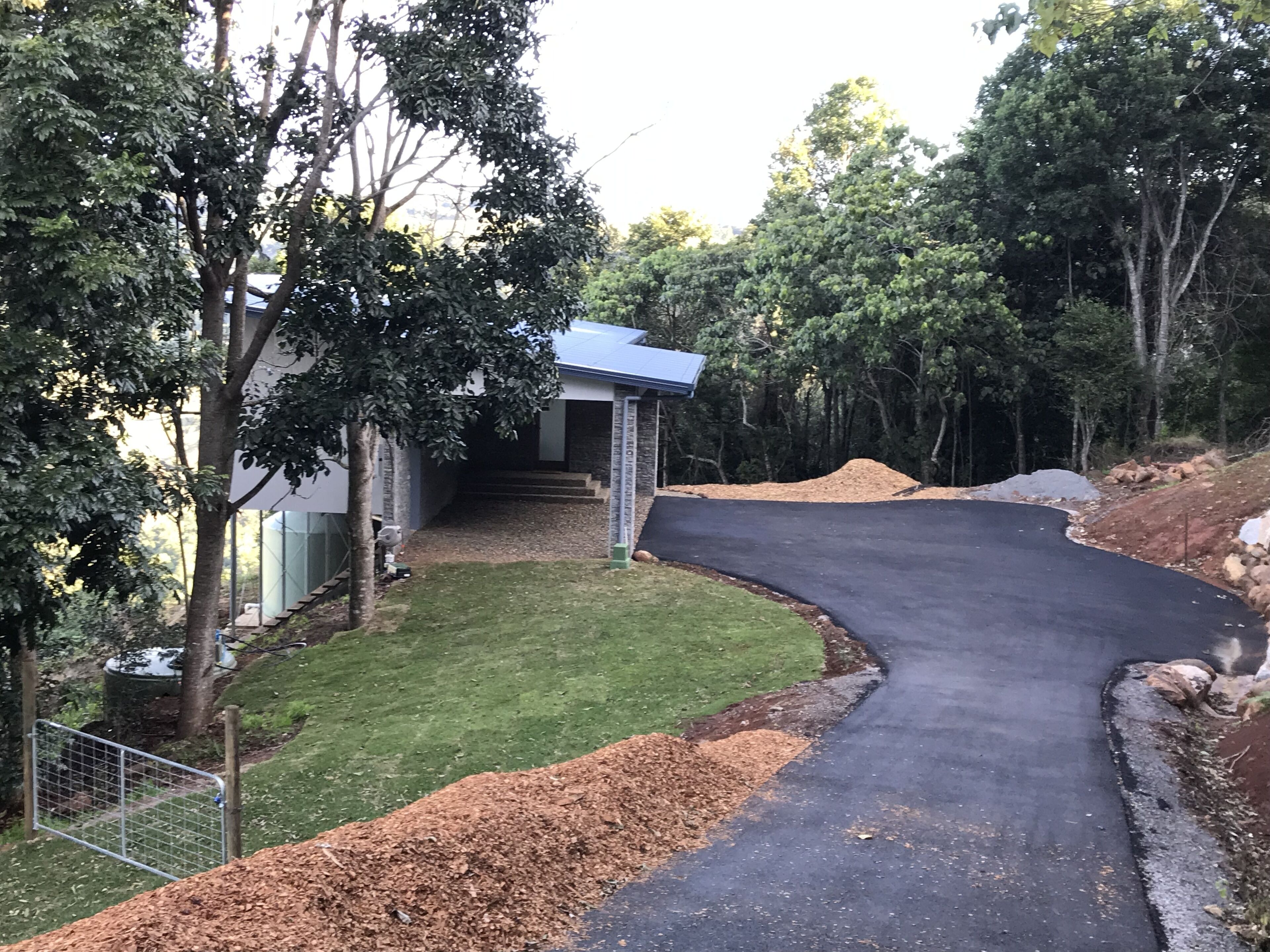 A driveway leading to a house with a small porch and a fenced yard.