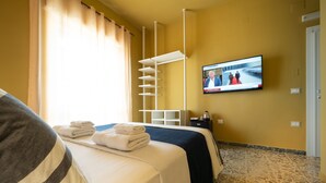Een hotelkamer met een bed, een aan de muur bevestigde televisie en een raam met gordijnen.