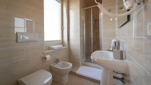 Een moderne badkamer met toilet, bidet, douche en wastafel.