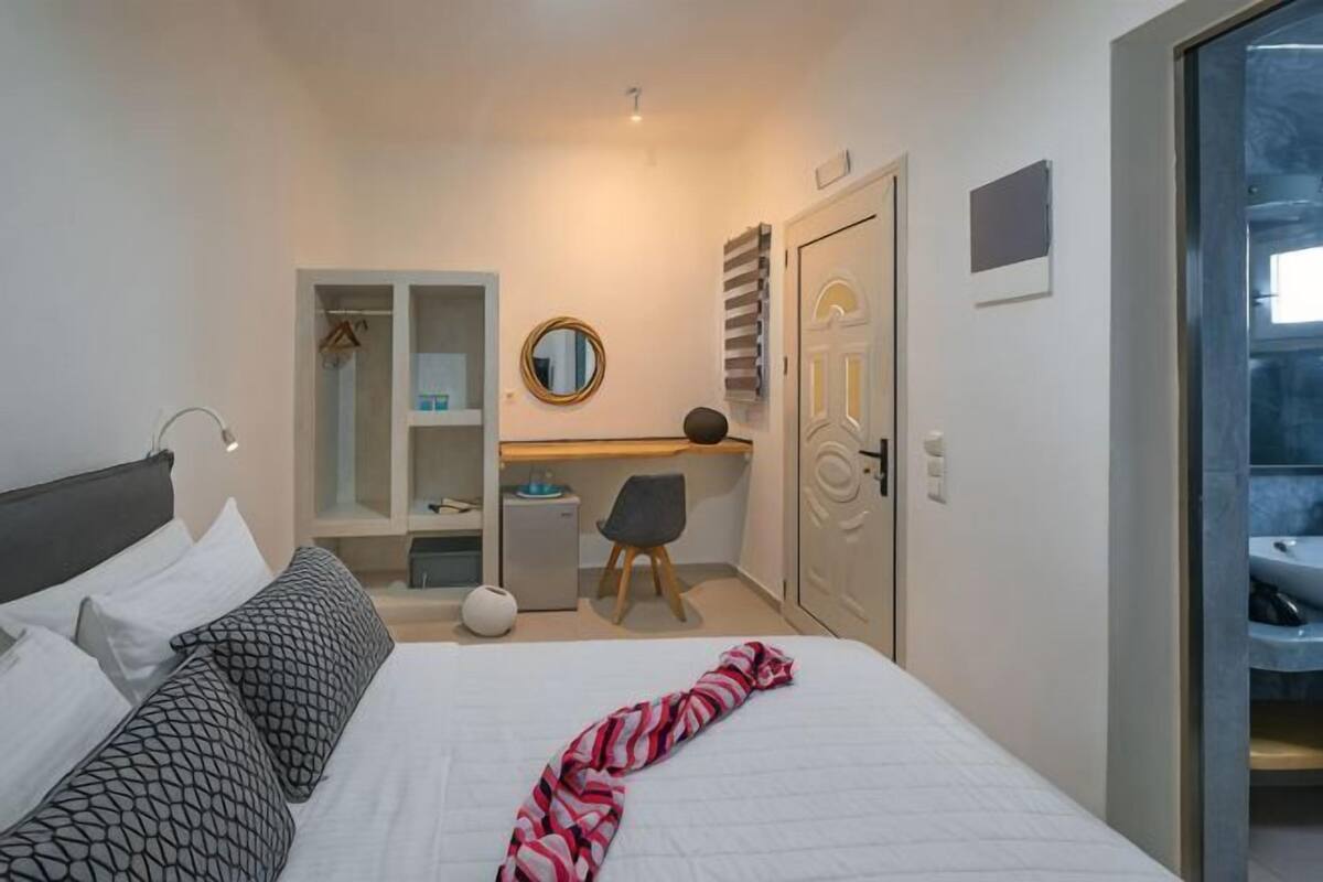 Een slaapkamer met een bed, nachtkastje, bureau, stoel, kledingkast en spiegel.