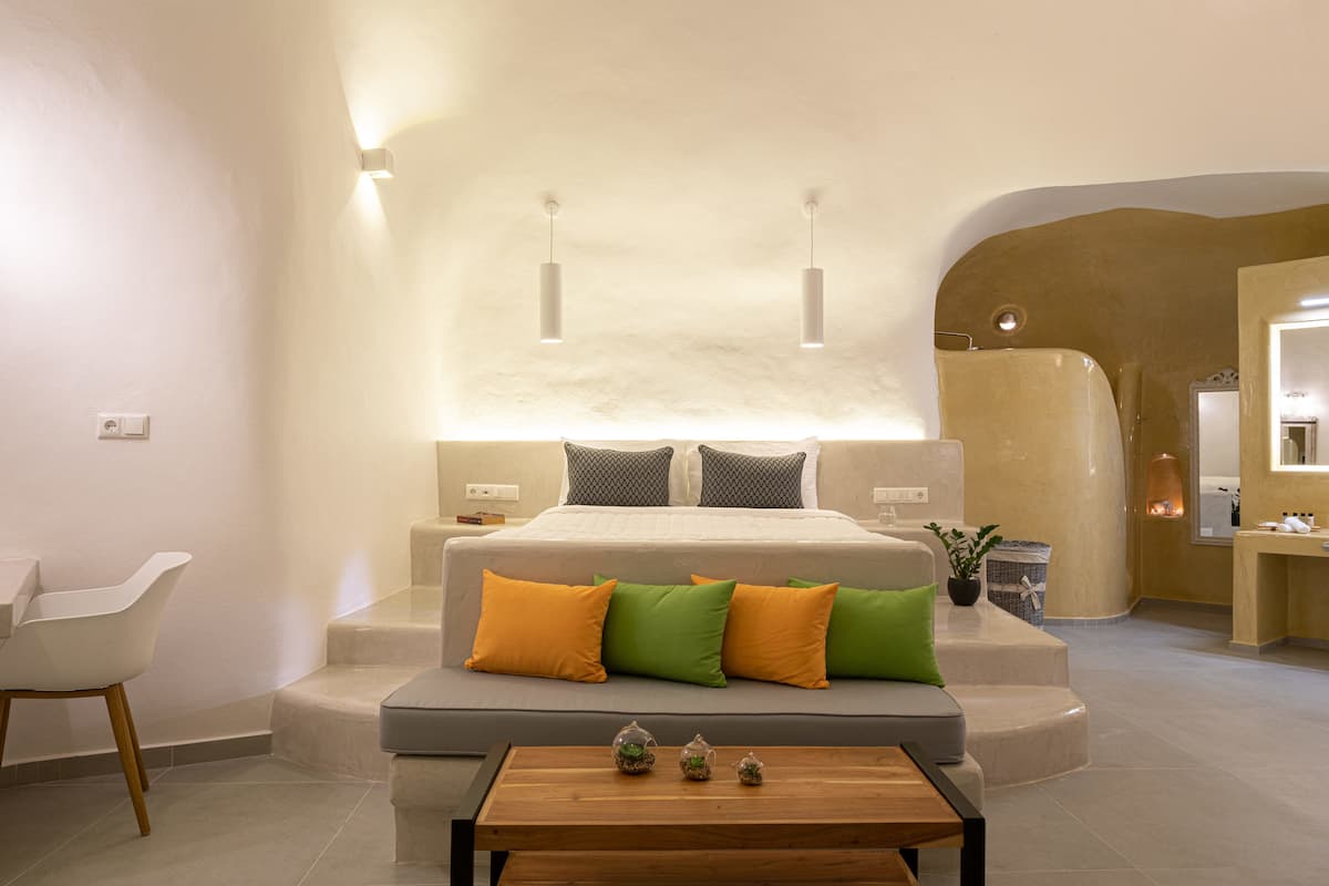 Een moderne slaapkamer met een groot bed, een zithoek en een klein tafeltje met decoratieve objecten.