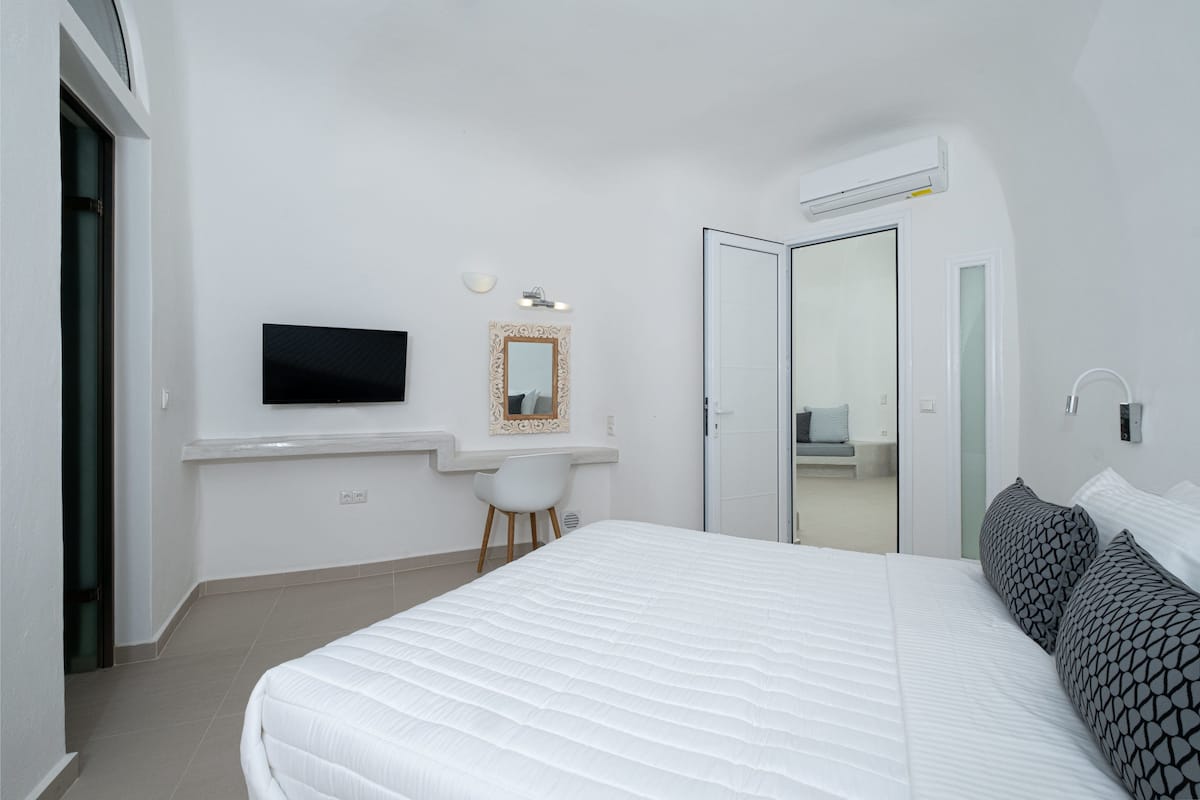 Een slaapkamer met een bed, een televisie, een bureau en een spiegel.