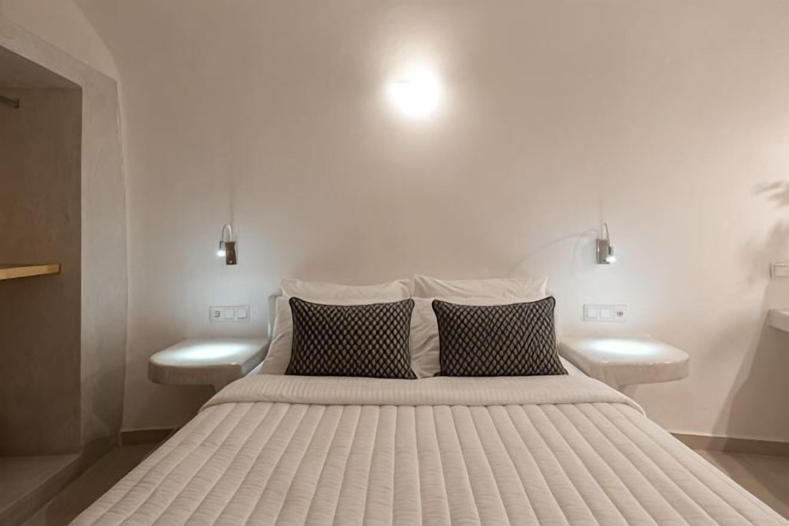Ein modernes Hotelzimmer mit einem großen Bett, zwei Nachttischen und Wandleuchten.