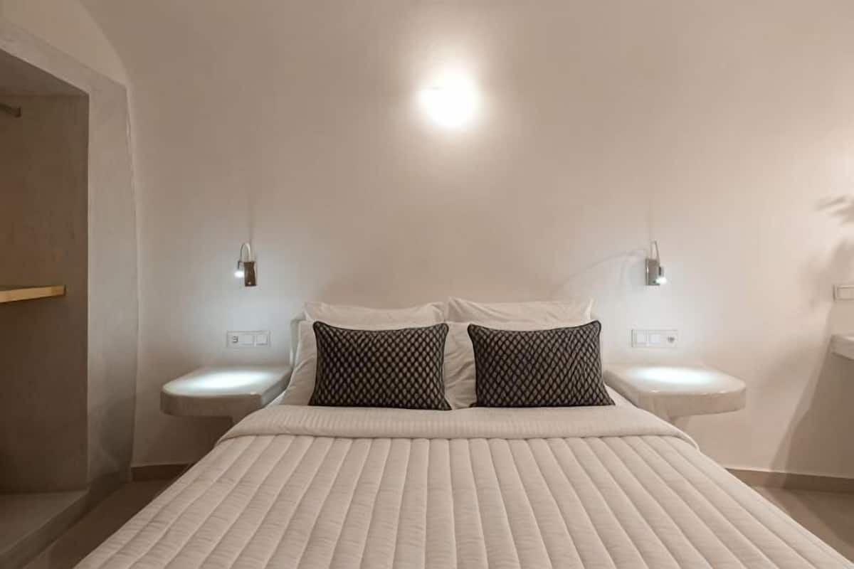 Een moderne hotelkamer met een groot bed, twee nachtkastjes en wandlampen.