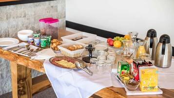 A breakfast buffet table with various food items, utensils, and condiments.