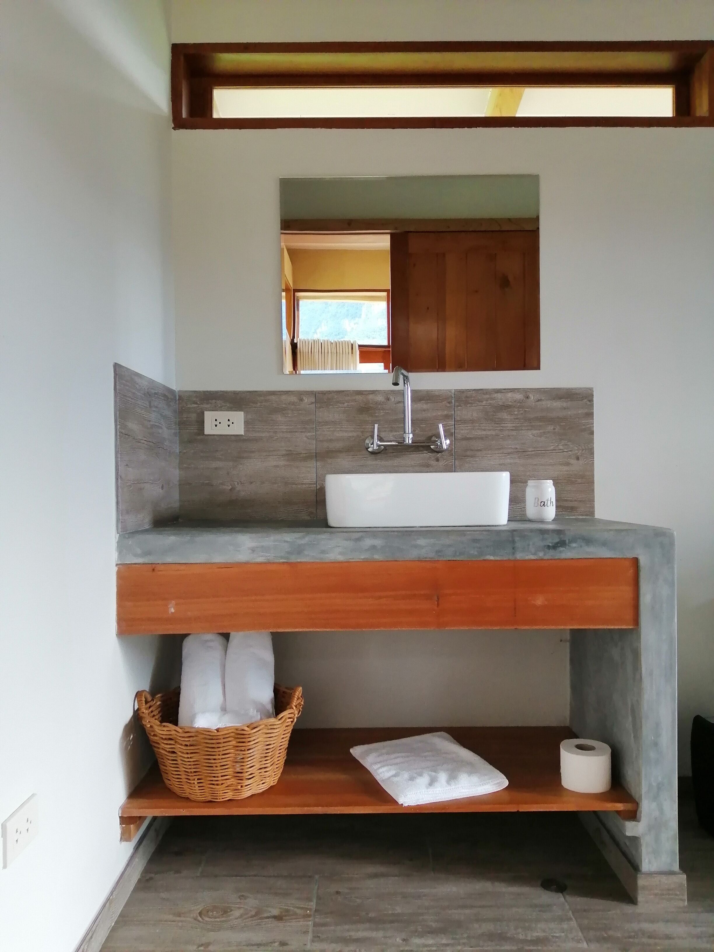 Ein Badezimmer mit einem Holzausleger, einem weißen Waschbecken und einem Spiegel darüber.
