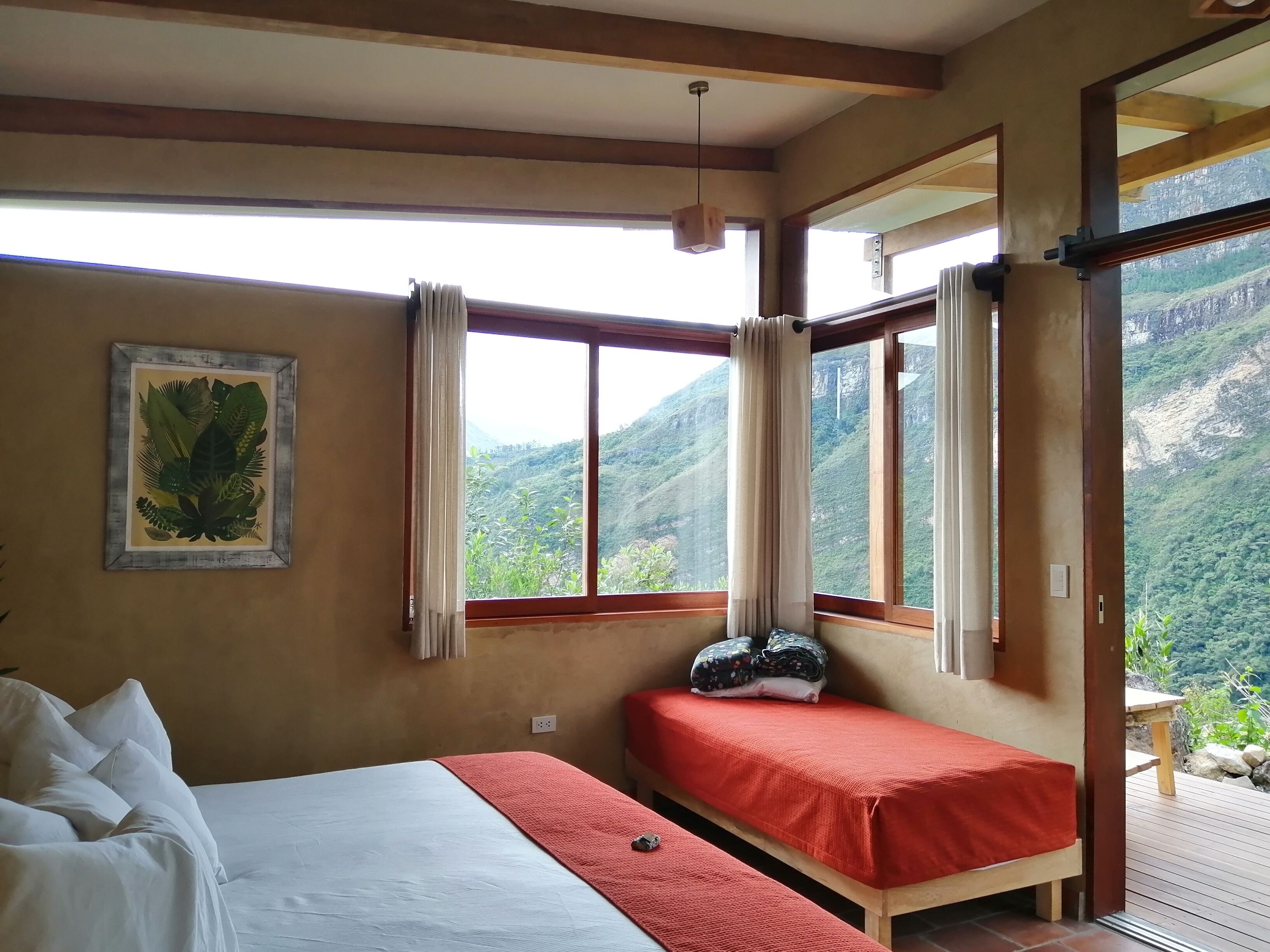 A bedroom with a bed, a bench, and a window with curtains.