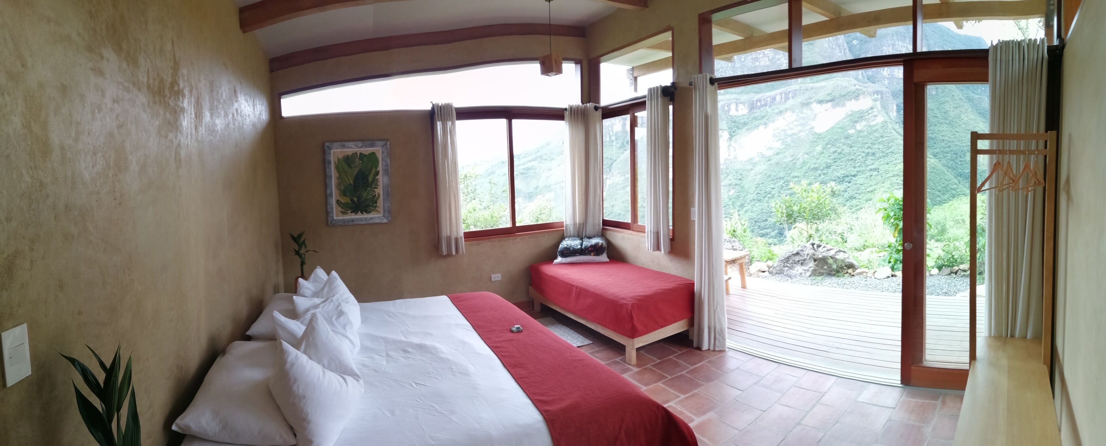 A bedroom with a large bed, a smaller bed, and a window with a view of a mountainous landscape.