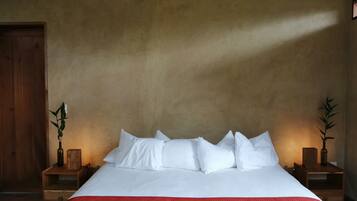 A bed with white bedding, a red throw blanket, and two nightstands with plants.