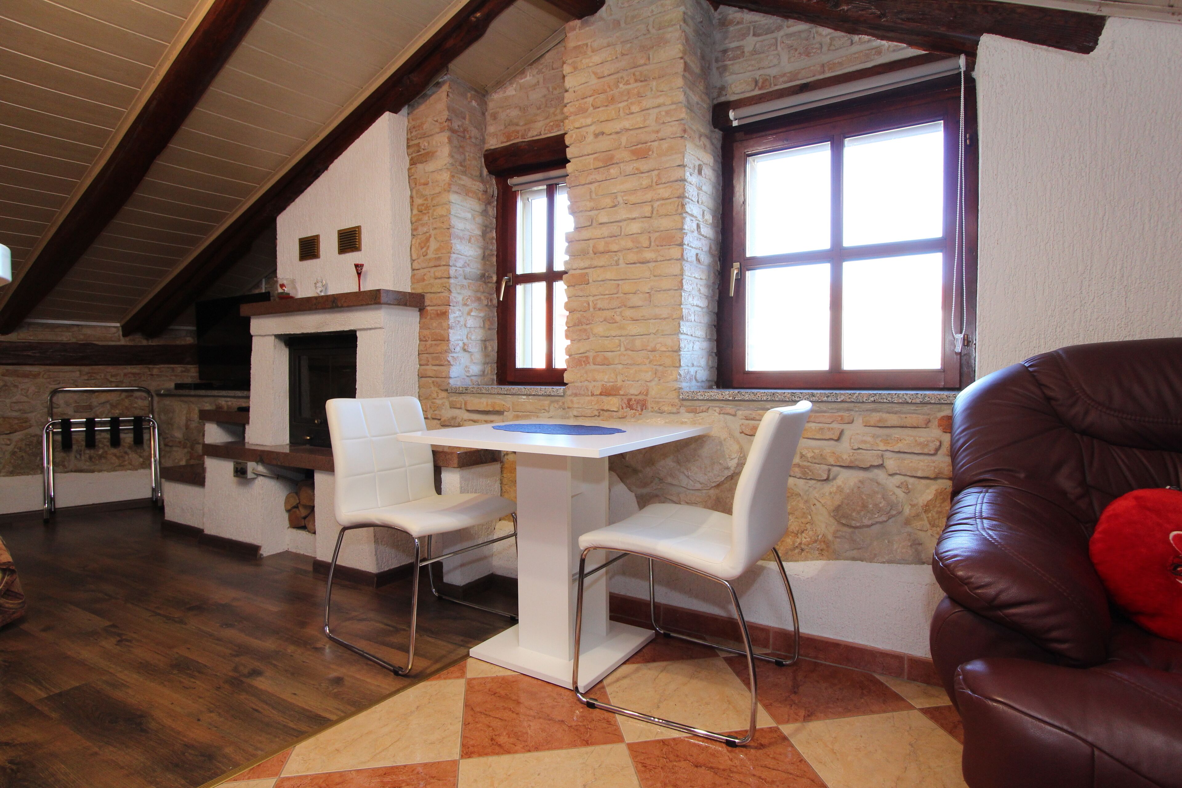Una habitación acogedora con chimenea, una mesa de comedor con sillas y un sofá de cuero.