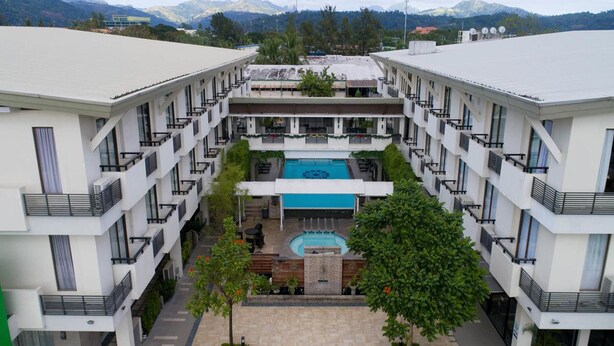 A modern hotel with a central courtyard featuring a pool, surrounded by multiple floors with balconies. - Mansion Garden Hotel (Olongapo)