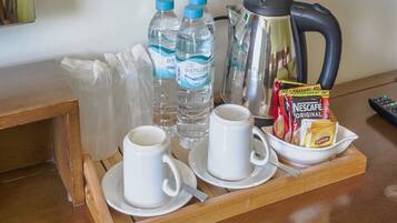 Una bandeja con una cafetera, dos tazas, dos botellas de agua y un sobre de café instantáneo Nescafe Original.