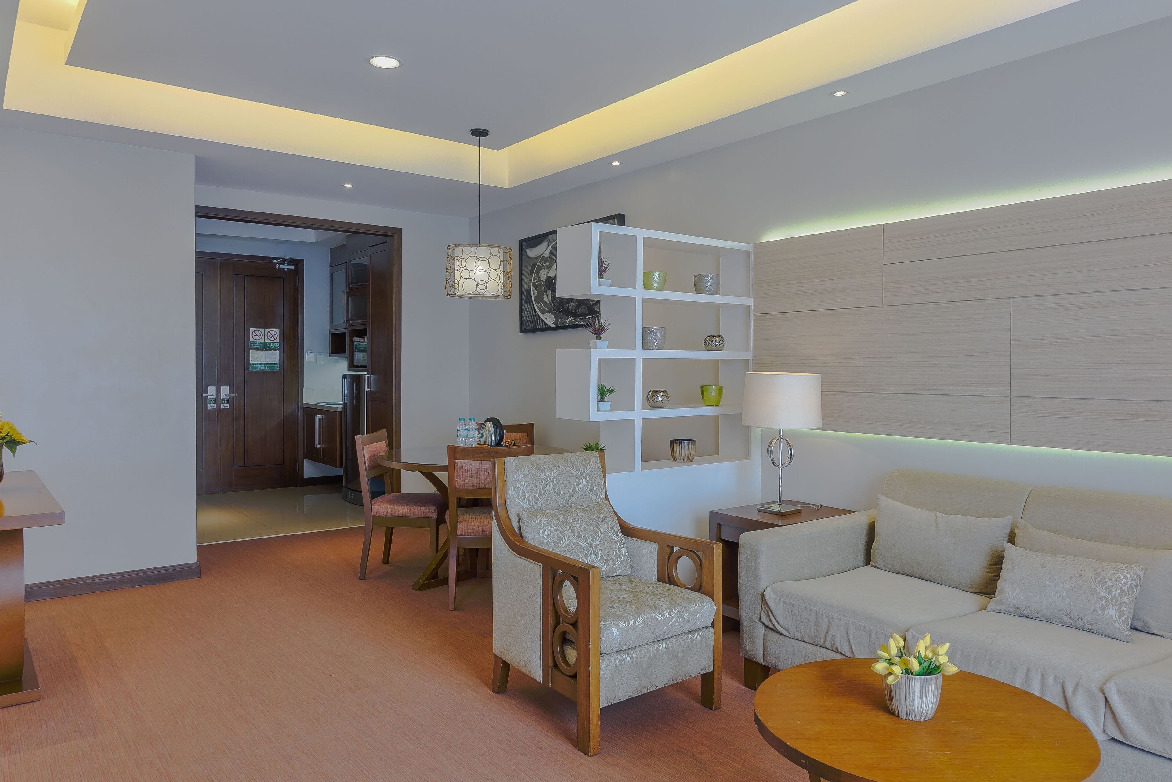 A modern living room with a sofa, armchair, coffee table, and a bookshelf.