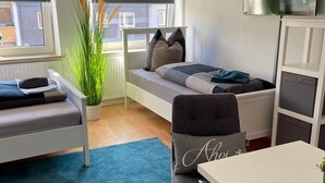 Ein modernes, kompaktes Wohnzimmer mit Bett, Sofa, Essbereich und an der Wand befestigtem Fernseher.