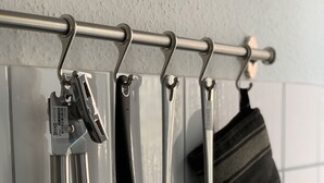 Eine Küche mit einem Metallregal, das verschiedene Küchenutensilien und einen schwarzen Topf beherbergt.