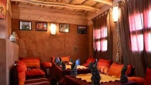 A traditional room with wooden beams, red upholstered sofas, and wall-mounted lamps. - Kasbah Des Montagnes (Ighil N'Oumgoun)