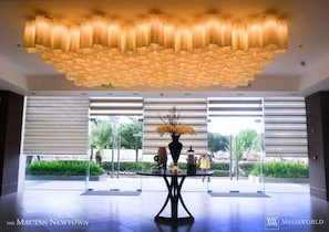 Experience the grandeur of The Mactan Newtown's lobby, featuring a stunning ceiling design and elegant round table with fresh flowers.