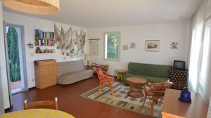 A cozy living room with a green sofa, wooden chairs, a small table, and a television. - Ripa Dei Carrai (Capoliveri)