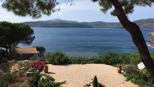 A coastal landscape with a sandy area, trees, and a view of the sea and distant mountains. - Ripa Dei Carrai (Capoliveri)