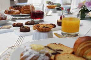 A breakfast setting with pastries, a glass of red juice, and a glass of orange juice on a table. - Hotel De La Ville Avellino (Avellino)