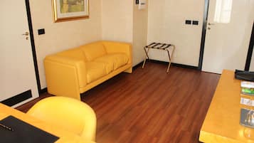 Una habitación con un sofá amarillo, un escritorio de madera y una pequeña estantería.