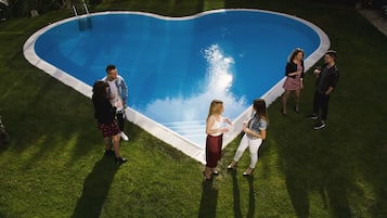 Guests can enjoy a refreshing swim in the heart-shaped pool surrounded by lush greenery.