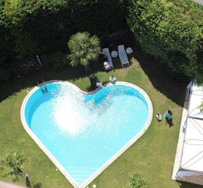 A heart-shaped swimming pool surrounded by grass and trees. - Hotel De La Ville Avellino (Avellino)