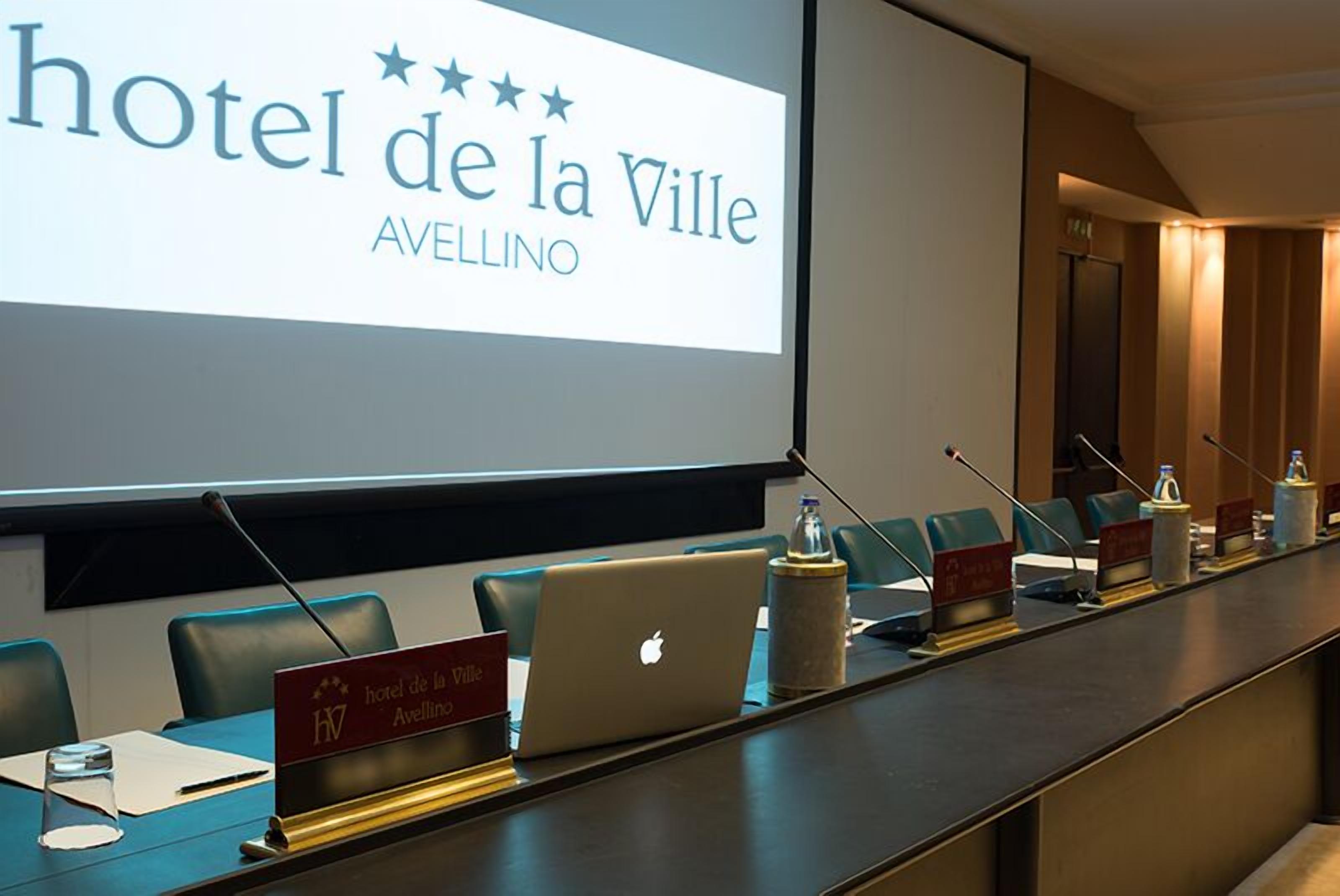 A conference room with a long table, nameplates, and a laptop.