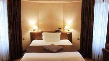 Habitación de hotel con una cama grande, dos lámparas de noche y una mesita de noche con un teléfono.